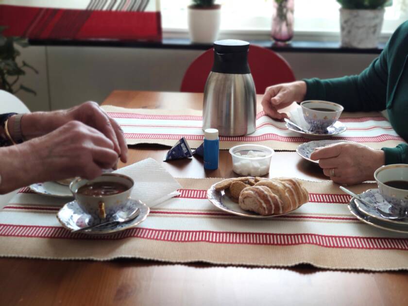 Kahvipöydässä, kahden ihmisen kädet näkyvät